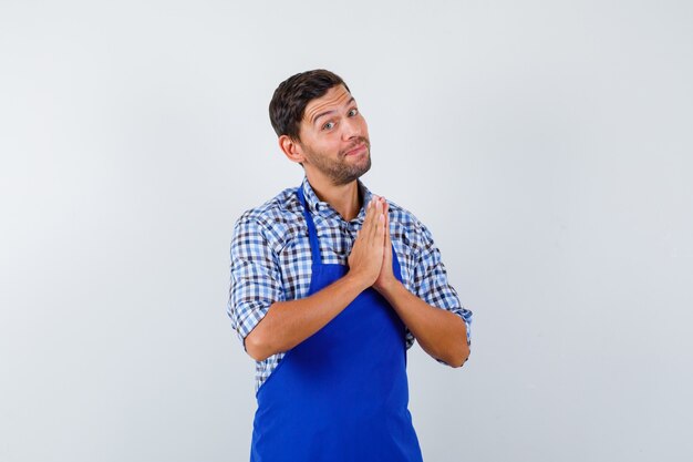 Jeune homme cuisinier dans un tablier bleu et une chemise