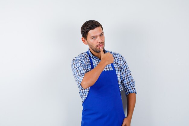 Jeune homme cuisinier dans un tablier bleu et une chemise