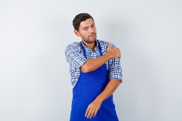 Jeune homme cuisinier dans un tablier bleu et une chemise