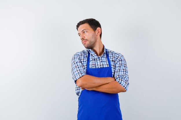 Jeune homme cuisinier dans un tablier bleu et une chemise