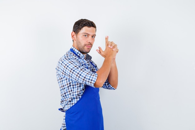 Jeune homme cuisinier dans un tablier bleu et une chemise