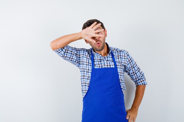 Jeune homme cuisinier dans un tablier bleu et une chemise