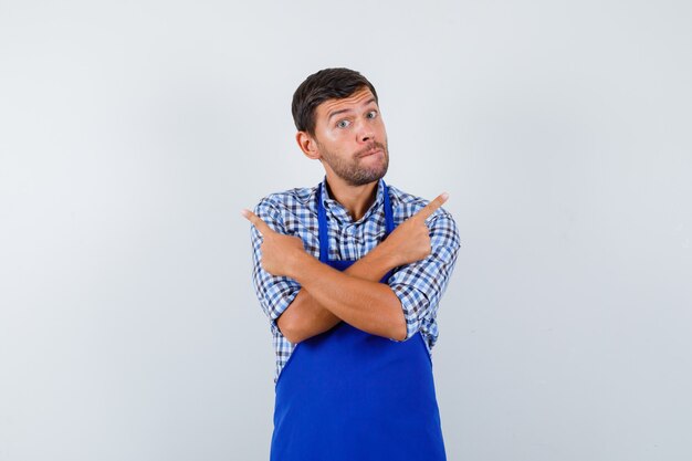 Jeune homme cuisinier dans un tablier bleu et une chemise