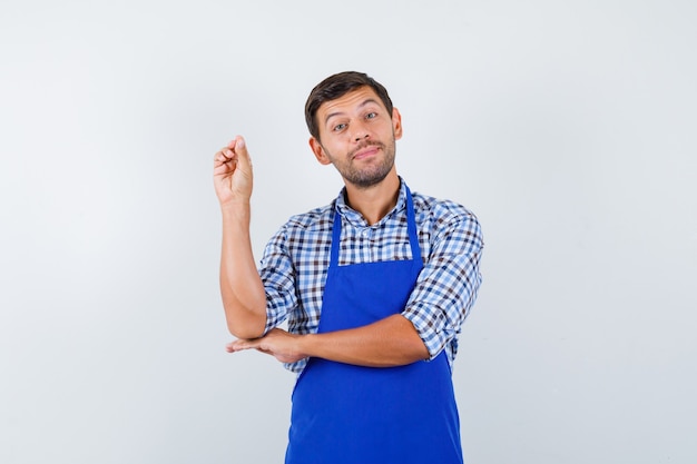 Jeune homme cuisinier dans un tablier bleu et une chemise