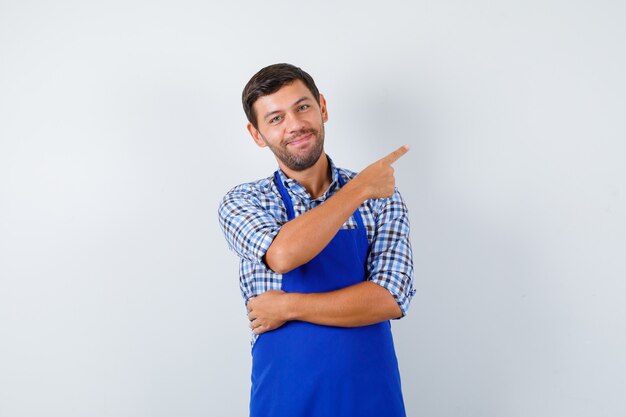 Jeune homme cuisinier dans un tablier bleu et une chemise