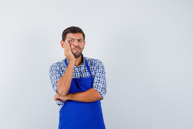 Jeune homme cuisinier dans un tablier bleu et une chemise