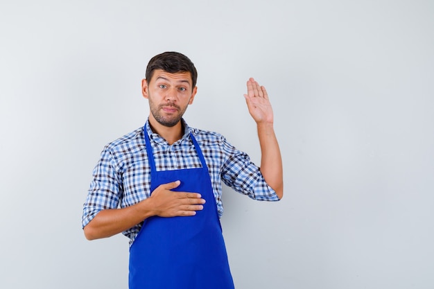 Jeune homme cuisinier dans un tablier bleu et une chemise