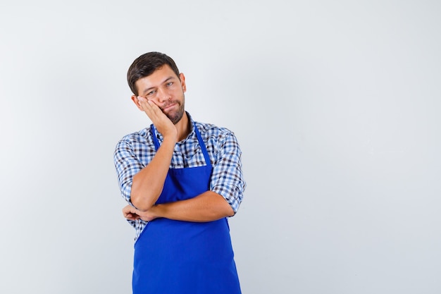 Jeune homme cuisinier dans un tablier bleu et une chemise