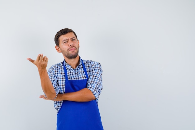 Jeune homme cuisinier dans un tablier bleu et une chemise