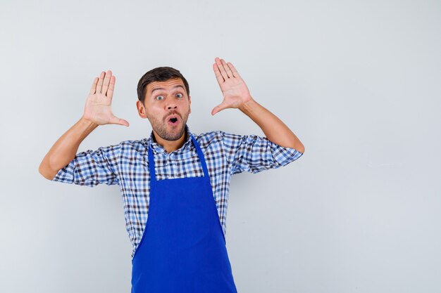 Jeune homme cuisinier dans un tablier bleu et une chemise