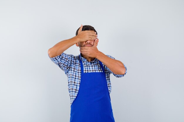 Jeune homme cuisinier dans un tablier bleu et une chemise