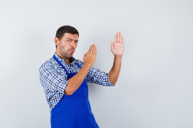 Jeune homme cuisinier dans un tablier bleu et une chemise