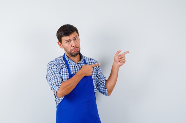 Jeune homme cuisinier dans un tablier bleu et une chemise