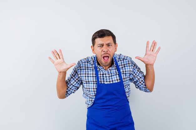 Jeune homme cuisinier dans un tablier bleu et une chemise