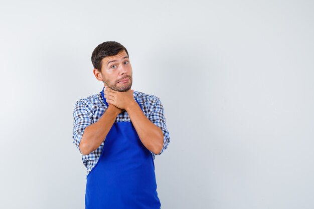 Jeune homme cuisinier dans un tablier bleu et une chemise