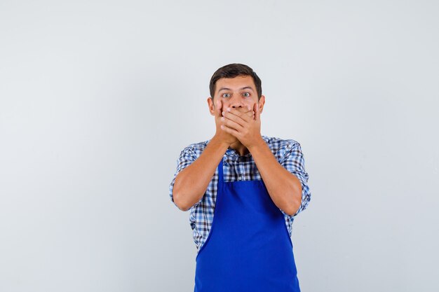 Jeune homme cuisinier dans un tablier bleu et une chemise