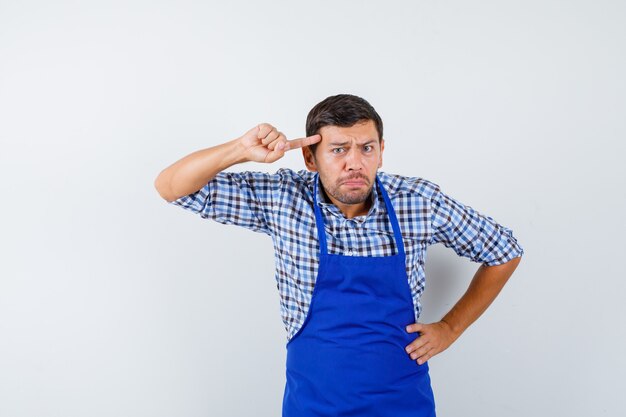 Jeune homme cuisinier dans un tablier bleu et une chemise