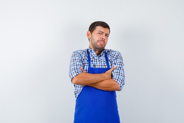 Jeune homme cuisinier dans un tablier bleu et une chemise