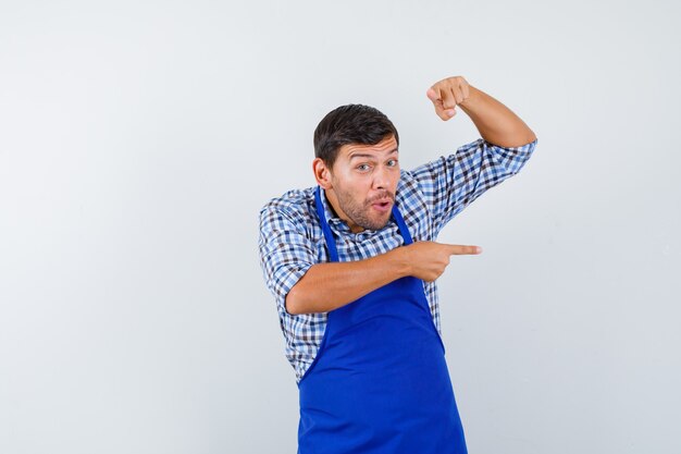 Jeune homme cuisinier dans un tablier bleu et une chemise