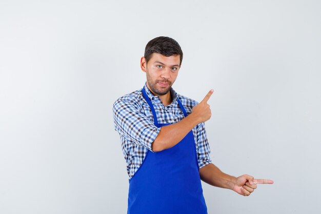 Jeune homme cuisinier dans un tablier bleu et une chemise