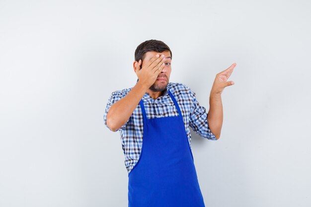 Jeune homme cuisinier dans un tablier bleu et une chemise