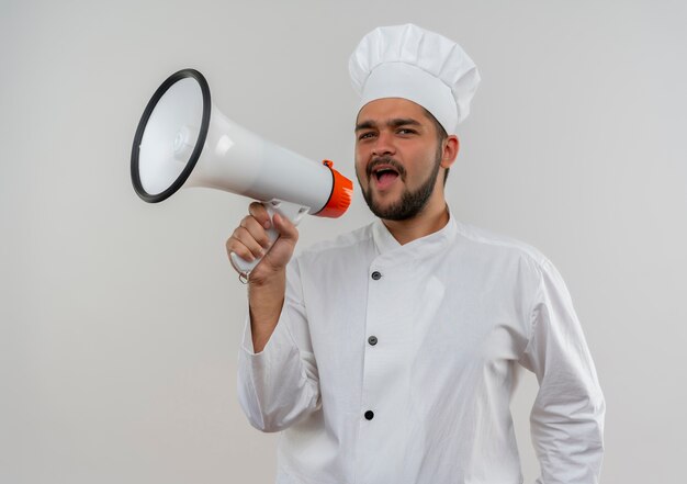 Jeune homme cuisinier en uniforme de chef criant dans haut-parleur à la recherche