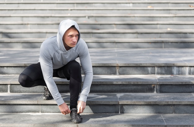 Jeune homme dans les escaliers attachant ses lacets