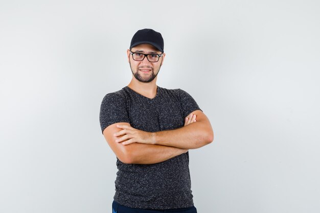 Jeune homme debout avec les bras croisés en t-shirt et casquette et à la confiance