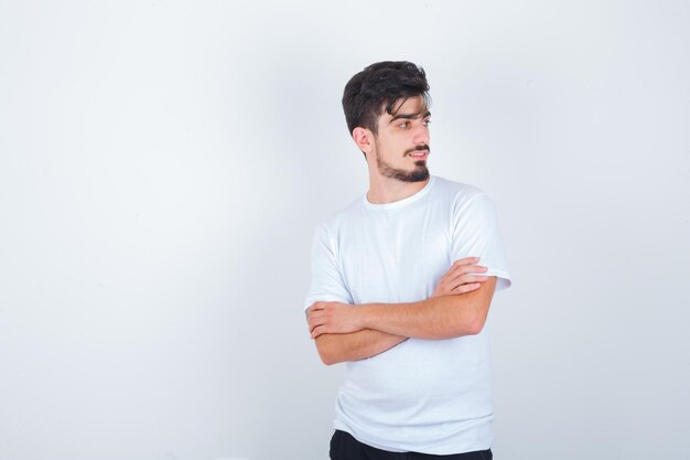 Jeune homme debout avec les bras croisés en t-shirt et à la charmante