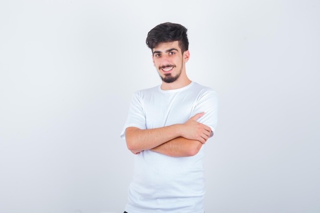 Jeune homme debout avec les bras croisés en t-shirt et à la confiance