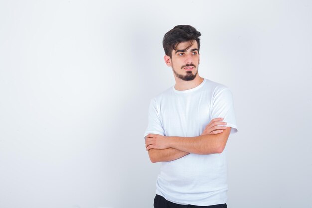 Jeune homme debout avec les bras croisés en t-shirt et à la mignonne