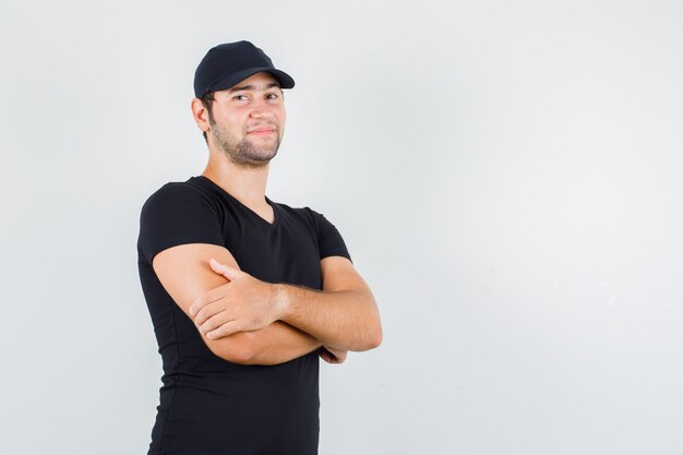 Jeune homme debout avec les bras croisés en t-shirt noir