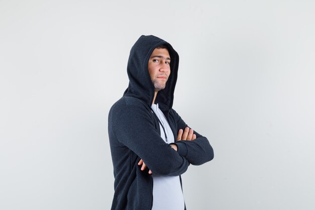 Jeune homme debout avec les bras croisés en t-shirt, veste et à la vue de face, confiant.