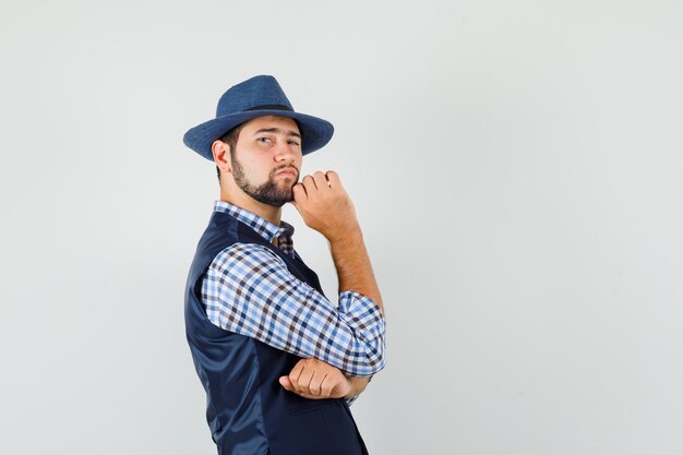 Jeune homme debout dans la pensée pose en chemise, gilet, chapeau et à la recherche de beau.