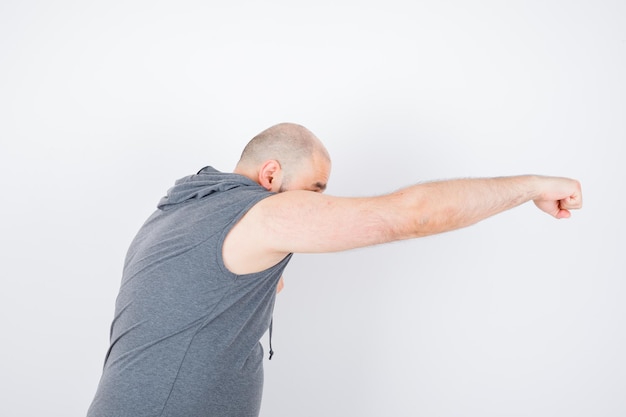 Jeune homme debout dans la pose de combat en sweat à capuche sans manches et l'air confiant. vue de face.