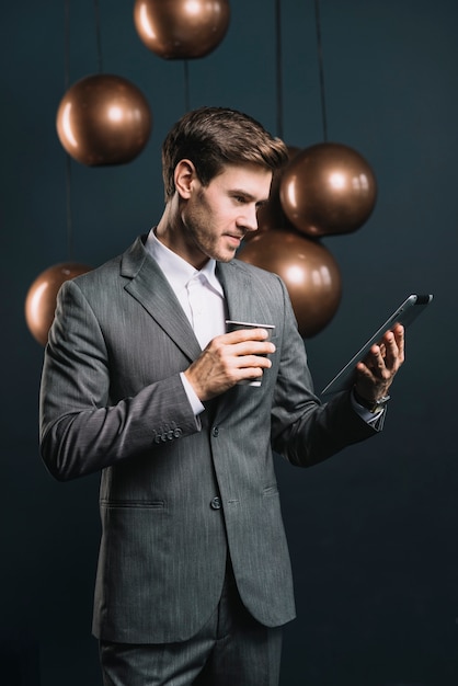 Jeune homme, debout, devant, miroir profilé, rond, lustre cuivre, regarder, tablette numérique