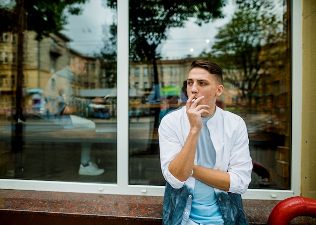 Photo gratuite jeune homme debout à l'extérieur du restaurant de fumer