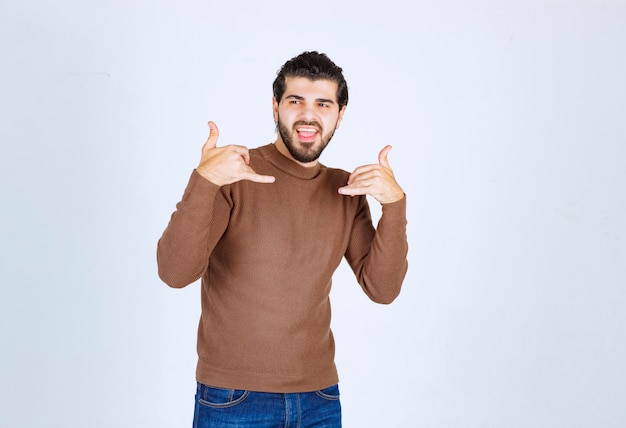 Jeune homme debout levant ses deux doigts comme prenant le téléphone isolé sur fond blanc. photo de haute qualité