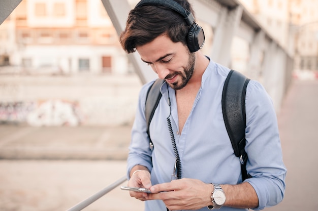 Jeune homme debout sur le pont en utilisant un smartphone