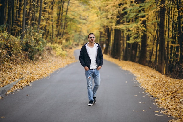 Jeune homme debout sur une route dans un parc en automne
