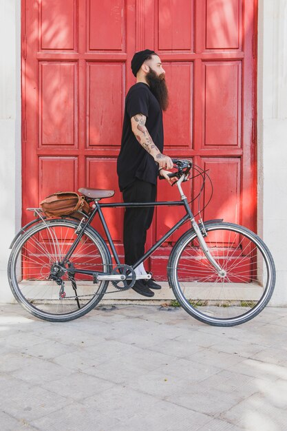 Jeune homme debout avec son vélo à la recherche de quelqu&#39;un