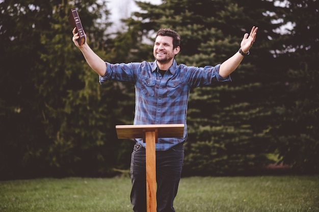 Photo gratuite jeune homme debout et tenant la bible dans ses mains