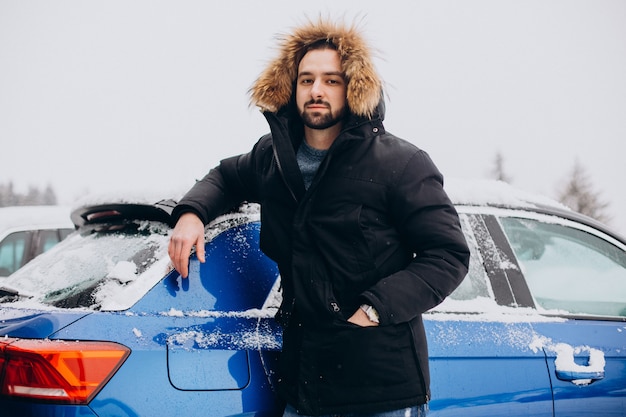 Jeune homme debout en voiture recouverte de neige