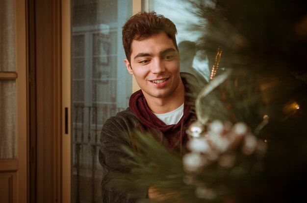 Jeune homme décorer un sapin de Noël