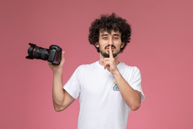 Jeune homme demandant de garder le silence et tenant une photocamera