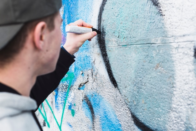 Jeune homme dessin graffiti sur le mur de la rue