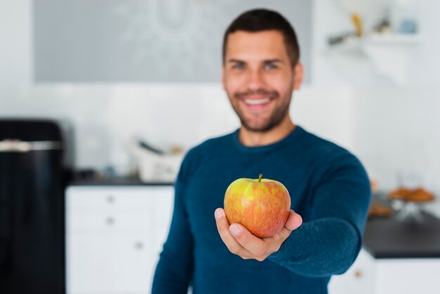 Jeune homme donnant à la caméra des fruits sains