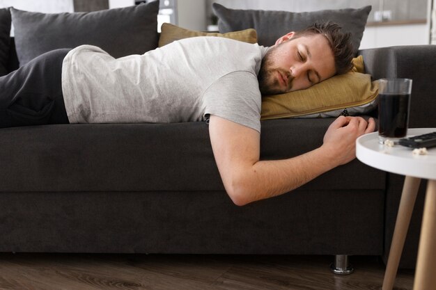 Jeune homme dormant sur le canapé à la maison