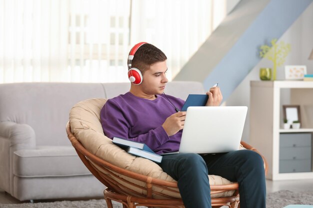 Jeune homme écoutant un livre audio à la maison