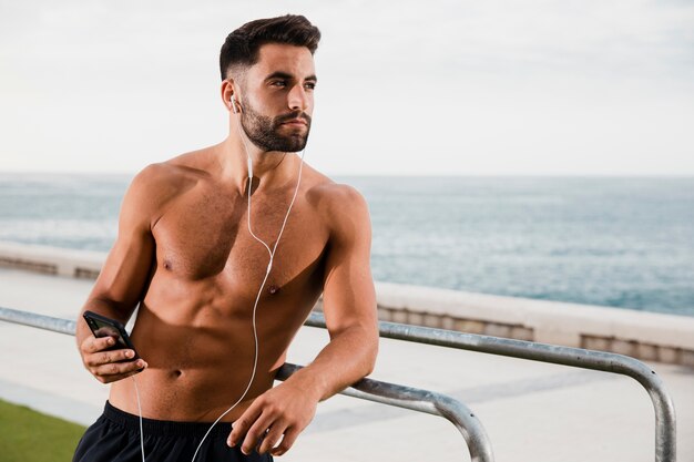 Jeune homme écoutant de la musique au bord de la mer